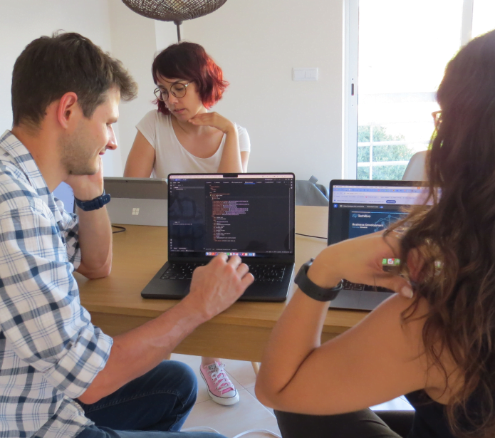 Founder of TechRivo sitting down with two workers at a table, loking at a computer, discussing It consulting services